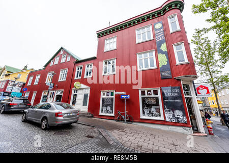 Reykjavik, Islande - 19 juin 2018 : route trottoir rue humide au centre-ville centre et panneaux pour magasin d'aliments sur la construction dynamique de couleur rouge exter Banque D'Images