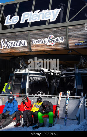 Porter des vêtements chauds aux couleurs vives les skieurs assis sur un banc au Le Pleney en gondole à Morzine Haute Savoie Portes du Soleil France Banque D'Images