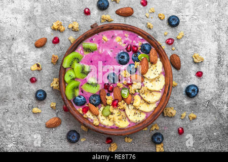 Bol à smoothie avec les baies fraîches, fruits, noix, graines et granola fait maison pour le petit-déjeuner végétarien végétalien sain. Vue de dessus Banque D'Images