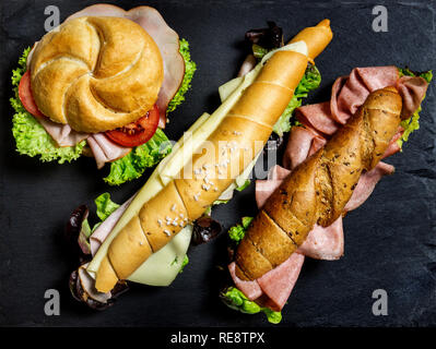 Deli sandwich sain complète kornspitz européenne bâtons bretzel de grains entiers et salzstangerl bun de pain rempli de tranches de viande et de salade sur dark ba Banque D'Images