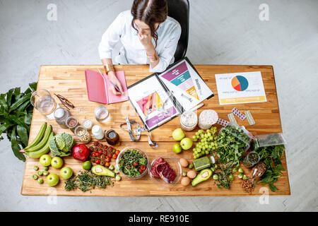 Diététiste écrit de régime, vue du dessus sur la table avec des produits sains et des dessins sur le thème de la saine alimentation Banque D'Images