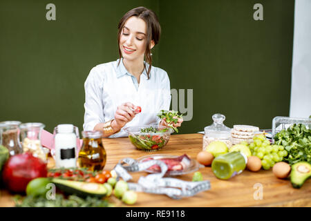 Diététiste femme travaillant sur un régime sain de faire une salade avec différentes matières premières sur le lieu de travail Banque D'Images