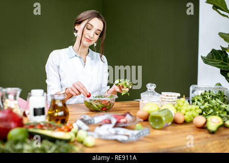Diététiste femme travaillant sur un régime sain de faire une salade avec différentes matières premières sur le lieu de travail Banque D'Images