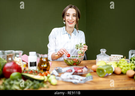 Diététiste femme travaillant sur un régime sain de faire une salade avec différentes matières premières sur le lieu de travail Banque D'Images