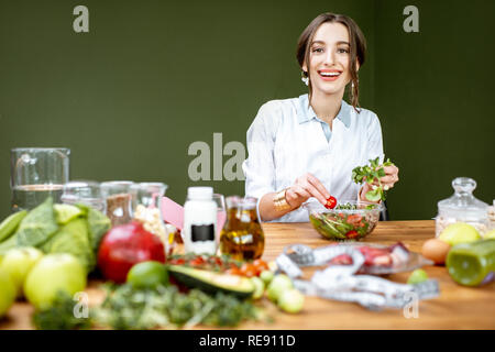 Diététiste femme travaillant sur un régime sain de faire une salade avec différentes matières premières sur le lieu de travail Banque D'Images