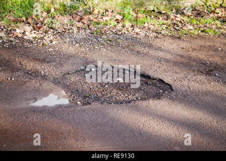 Poule en route de campagne et de la campagne anglaise. Route asphaltée qui nécessitent une réparation, la conduite dangereuse surface. Banque D'Images