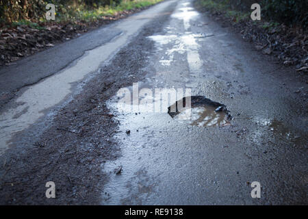 Poule en route de campagne et de la campagne anglaise. Route asphaltée qui nécessitent une réparation, la conduite dangereuse surface. Banque D'Images