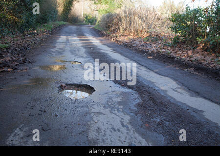 Poule en route de campagne et de la campagne anglaise. Route asphaltée qui nécessitent une réparation, la conduite dangereuse surface. Banque D'Images