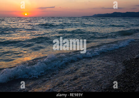 Coucher du soleil sur la mer d'été sur la plage de galets, le soleil, les vagues et les nuages, de beaux éclairages spectaculaires Banque D'Images