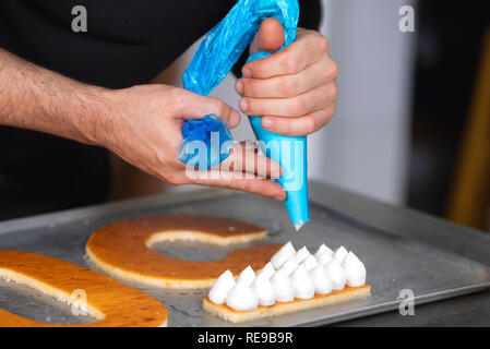 Vue en gros, les mains du chef avec la préparation d'une crème sac confiserie fiftie ans cake pâtisserie cuisine . Banque D'Images