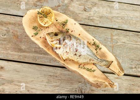 Le poisson cuit farci de citrons, vers le bas. Prepareed dorado poisson sur plaque de bois et garnir de citrons farcis autour. Banque D'Images