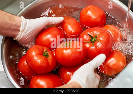 Les tomates dans l'eau de rinçage dans bol en métal. Lave-mains Chef tas de tomates dans l'eau. Banque D'Images