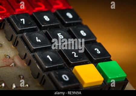 Un vieux pavé numérique avec d'autres boutons (noir, jaune, vert), allongé sur une table en bois Banque D'Images