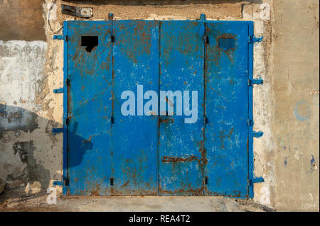 Rusty blue metal porte de garage dans un mur de pierre weatherbeaten Banque D'Images