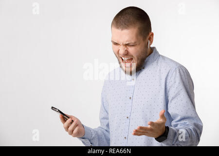 Homme barbu utilise des écouteurs sans fil et smartphone Banque D'Images