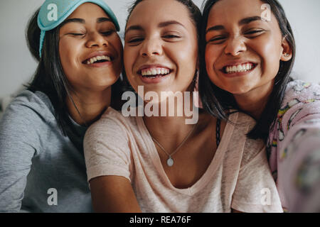 Trois jeunes filles s'amusant rire et posant pour. selfies Les jeunes filles s'amusant pour un sourire pendant une soirée pyjama selfies. Banque D'Images