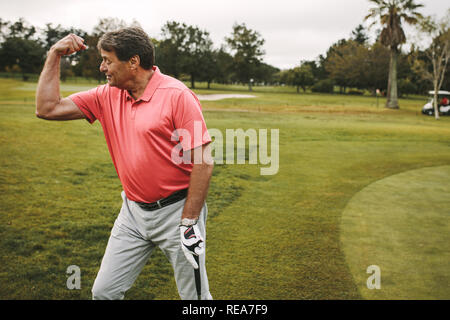 Man célébrant un trou en un sur le terrain de golf. Man flexing ses biceps après avoir fait un score à la golf. Banque D'Images