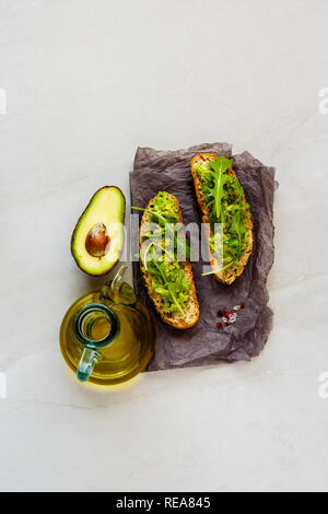 Toasts Frais d'avocat et de roquette mise à plat. Les bons gras matières concept de saine alimentation. Banque D'Images