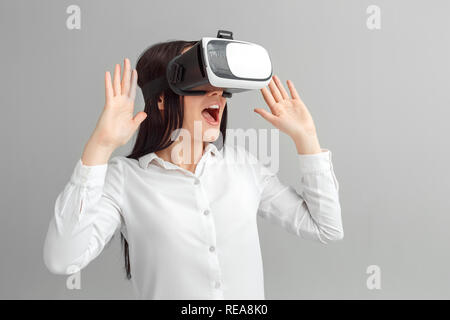 Freestyle. Femme au casque de réalité virtuelle isolés sur gris regardant la vidéo excité Banque D'Images