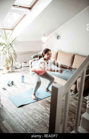 Cheerful young woman doing des exercices spéciaux pour la mise en place de la partie inférieure du corps Banque D'Images