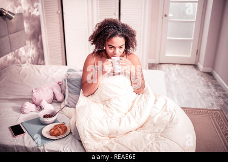 Une jeune femme avec des cheveux bouclés prévues matin paisible Banque D'Images