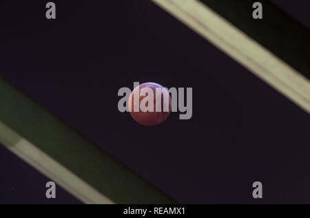 21 janvier 2019, Hessen, Frankfurt/Main : Comme un rouge, soi-disant 'blood moon', la pleine lune se tient entre les poutres du pont de rafting, bien qu'il pas dans l'ombre de la terre à la base. Un avion commercial laisse ses traces en face de la terre au cours d'un satellite d'exposition plus long temps. Photo : Frank Rumpenhorst/dpa dpa : Crédit photo alliance/Alamy Live News Banque D'Images