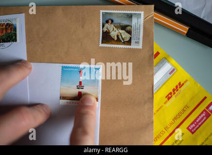 21 janvier 2019, Berlin : ILLUSTRATION - Un homme s'enfonce un timbre sur une enveloppe. Photo : Monika Skolimowska/dpa-Zentralbild/ZB Banque D'Images