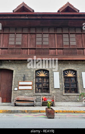 Guy de dormir sur un banc-El Amanecer immeuble sur General Luna, St.-mur en pierre et fer à repasser à Windows grille rez-de-rangée de oriels en treillis en bois Banque D'Images