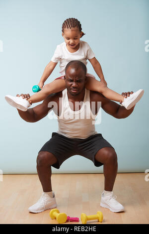 Beau black jeune père est en train de faire des squats avec sa jolie petite fille lui. Il a des problèmes avec un poids supplémentaire, ce qui est rigolo à h Banque D'Images