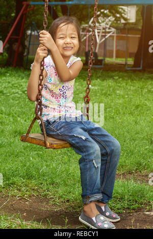 Portrait d'active asian girl sitting in park balançoires Banque D'Images