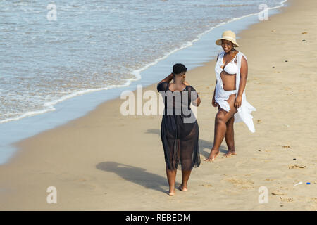 Une grande femme noire portant un bikini blanc et un chapeau qui pose pour son ami qui prend ses photos de la plage de Durban, Afrique du Sud. Banque D'Images