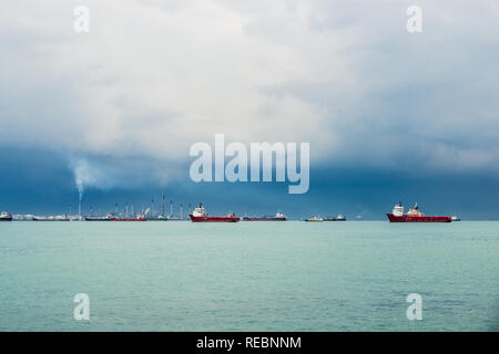 Vue sur le détroit de Singapour à partir de l'île de Sentosa. Les navires, les paysages industriels et de mauvais temps. Banque D'Images