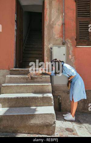 Jeune femme de caresser un chat sur la rue de l'Italie. Billet, concept de soins animaux Banque D'Images