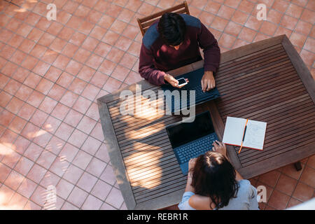 Vue de dessus de l'homme et la femme travaillant sur ordinateur portable en fond de table en bois concept freelance. Banque D'Images