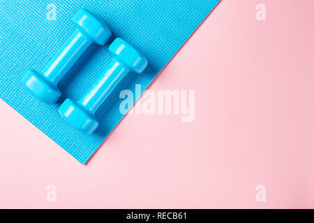 Le minimalisme Fitnes concept. Les haltères et sport bra sur bleu et rose vue d'en haut backgroundm Banque D'Images