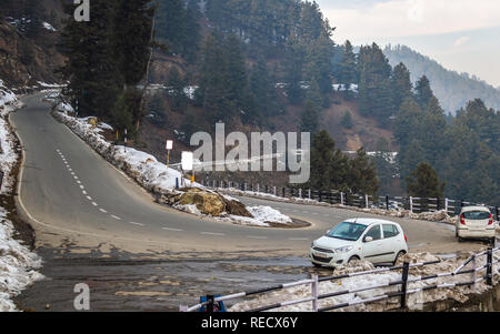 Gulmarg, Jammu-et-Cachemire, l'Inde Date : Novembre 15, 2018-- le long des côtés de la neige des routes sinueuses sur terrain vallonné avec des voitures garées Banque D'Images