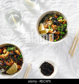 Deux poke bol. Le tofu, le riz, les algues, les pois verts et oignons savoureux et sain de la nourriture végétarienne. Vue supérieure mise à plat Banque D'Images