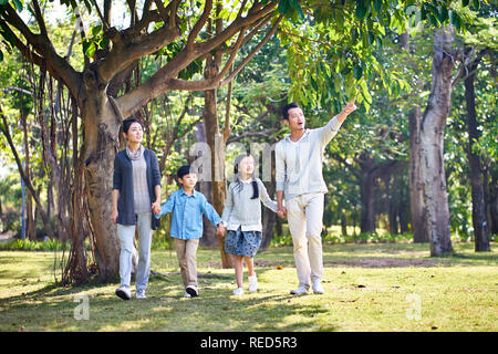 Famille avec deux enfants asiatiques marche main dans la main à l'extérieur dans le parc. Banque D'Images