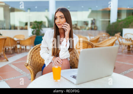 Belle jeune femme avec un verre de limonade et laptop in cafe Banque D'Images