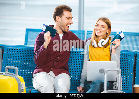 Cheerful couple de nationalités avec l'air des billets à l'aéroport proche d'assurance Banque D'Images