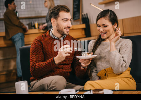 Bel homme recherche femme à surpris et holding cake in cafe Banque D'Images