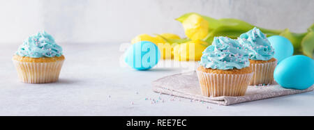 Vanille Pâques cupcakes avec glaçage au fromage à la crème, des œufs et des tulipes. Joyeuses Pâques bannière. Banque D'Images