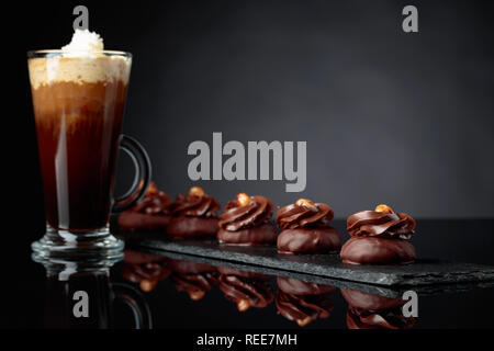 Dessert avec chocolat noisette et café avec de la crème sur un fond réfléchissant noir. Copie de l'espace pour votre texte. Banque D'Images