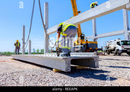 Gréeur est la fixation crochet de grue à la poutrelle en béton pour le levage de la structure d'assemblage. Banque D'Images