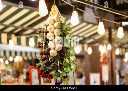 Gousses d'ail suspendue sur une ligne d'ampoules le long du côté raisins verts et rouges. Très artistique. Banque D'Images