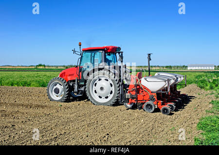 Avec un tracteur agriculteur sème du maïs sur son domaine. Banque D'Images