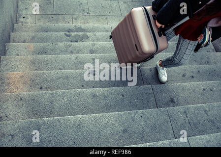 Femme faisant glisser une valise trolley de monter les escaliers d'un passage inférieur. Banque D'Images