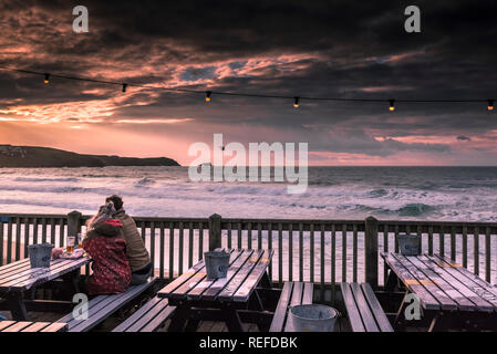 Un couple de regarder un magnifique coucher de soleil, assis sur une terrasse de la plage de Fistral Newquay Cornwall au bar. Banque D'Images