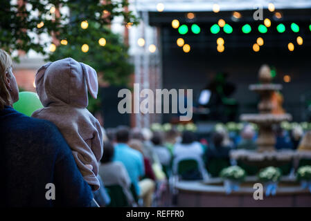 Maman tient son fils ou fille à capuche avec oreilles de lapin et profiter de la culture. Soirée romantique dans les spectacles avec des musiciens de jazz s Banque D'Images