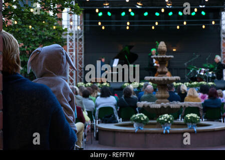 Maman tient son fils ou fille à capuche avec oreilles de lapin et profiter de la culture. Soirée romantique dans les spectacles avec des musiciens de jazz s Banque D'Images